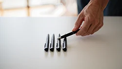 Рука поправляет ручку, лежащую на столе